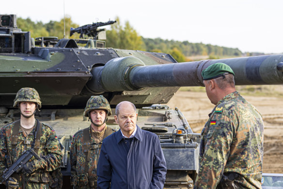 German Chancellor Olaf Scholz, in blue, talks to German soldiers by a Leopard 2 main battle tank during an exercise in Ostenholz, Germany, in October.