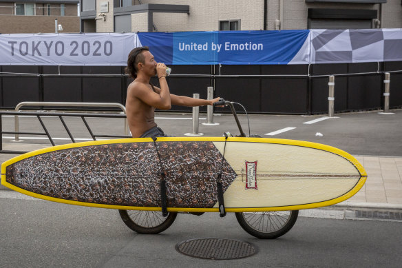 A surfer cycles past an Olympic banner in Fujisawa in June. 
