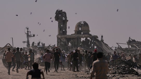 Palestinians collect leaflets dropped by an Israeli drone warning people to stay away from the so-called yellow line in Khan Younis, in the southern Gaza Strip, Monday, Oct. 20, 2025. (AP Photo/Jehad Alshrafi)