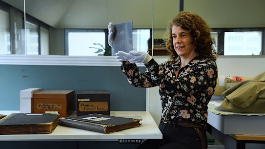 Laila Ellmoos a city archivist with City of Sydney looks at one of the glass plate negatives. 