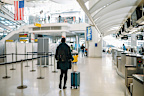 Female traveler arriving to the airport in New York, USA, pushing a stroller bag.