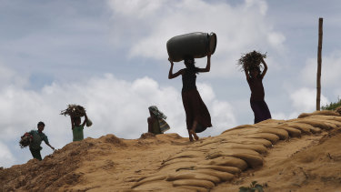 Rohingya girls carry firewood on their heads as they make their way through Kutupalong refugee camp.
