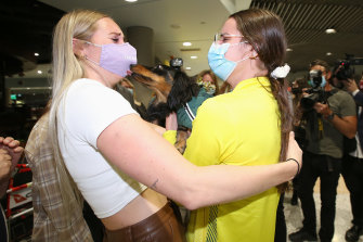 Kaylee McKeown (right) hugs her dog Ottis and sister Taylor McKeown at Brisbane Airport.