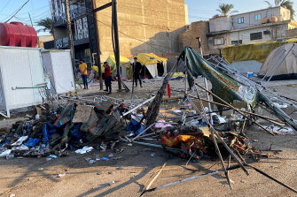 People inspect burned tents outside the heavily fortified Green Zone in Baghdad, Iraq, on Saturday, after at least one protester was killed and scores of people, mostly members of Iraqi security forces, were injured during protests. 