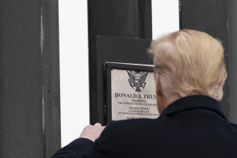 The president Donald Trump signs a plaque on a section of the border wall in January.