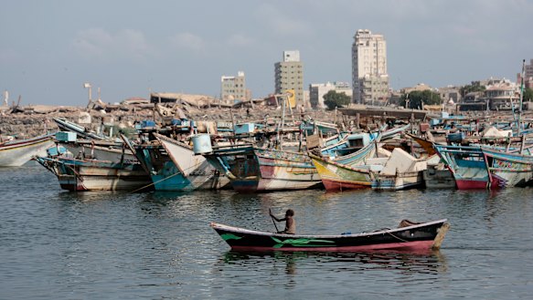 A fisherman paddles his boat past destroyed buildings on the coast of the port city of Hodeida, Yemen.