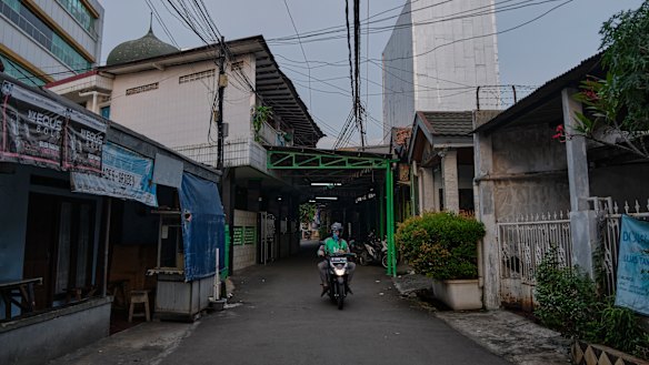 A motorcycle delivery driver cruises the empty street of a neighbourhood in Jakarta, Indonesia. 