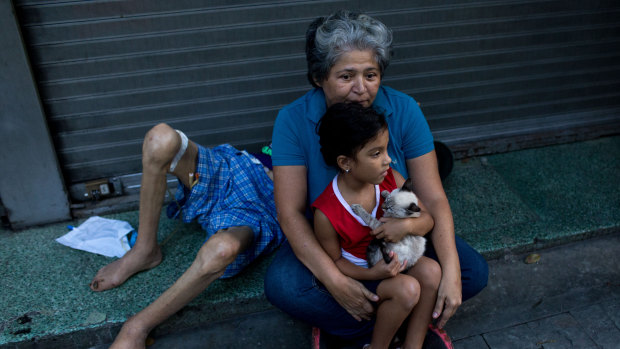 A woman holds a child outside in Caracas, following the earthquake.