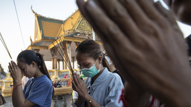 Cambodian women pray at a Buddhist shrine. Cambodia's tourism and real estate sectors could experience slowdowns due to the COVID-19. 