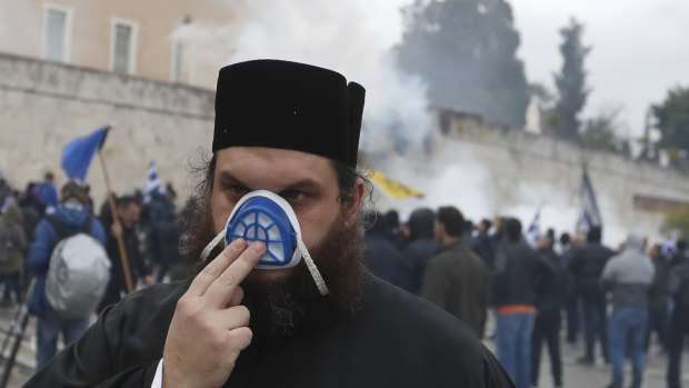 A monk protects himself from tear gas during clashes  in Athens on Sunday.