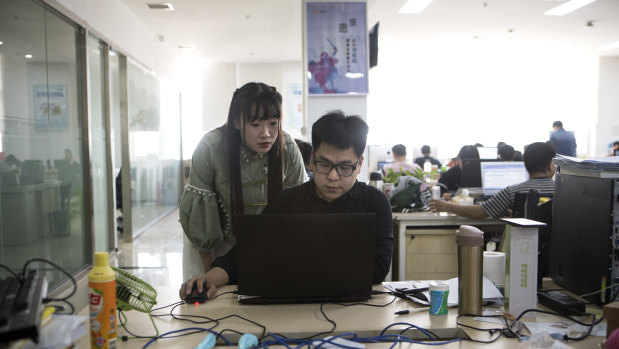 Shen Yue looks over the shoulder of one of her colleagues at the office.