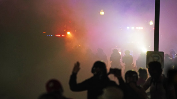 Police in riot gear clear the area in front of Kenosha County Courthouse during clashes with protesters.