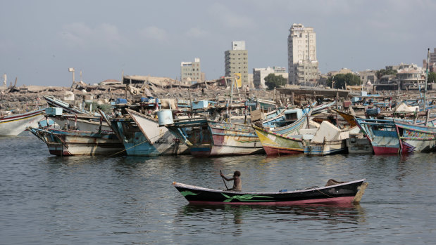A fisherman paddles his boat past destroyed buildings on the coast of the port city of Hodeida, Yemen.