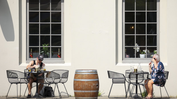 People sit in the sun outside a cafe in Wellington on Sunday. NZ is on level-two alert, while Auckland is in lockdown because of new cases.