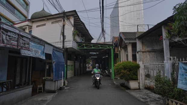 A motorcycle delivery driver cruises the empty street of a neighbourhood in Jakarta, Indonesia. 