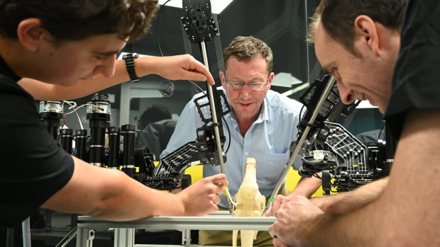 The prototype "SnakeBot overseen by Professor Ross Crawford (centre) PhD Researcher Andrew Razjigaev (left) and Centre Chief Investigator Jonathan
Roberts (right)