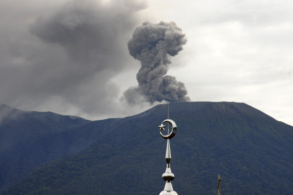 The minaret of a mosque is seen as Mount Marapi erupts.