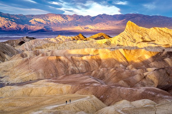 Hikers on the slopes of Zabriskie Point at sunrise.