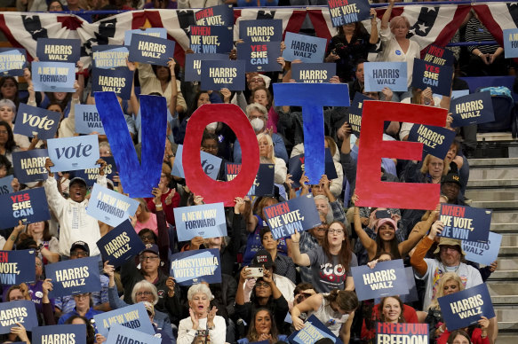 Attendees hold signs as former president Barack Obama speaks during a campaign rally supporting   Kamala Harris.