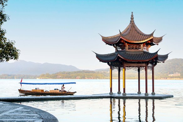 A traditional boat passes by the serene Jixian Pavilion on Hangzhou’s famous West Lake in the early morning.