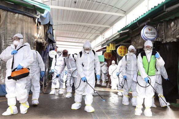 Workers wearing protective suits spray disinfectant as a precaution against the coronavirus at a market in Bupyeong, South Korea.