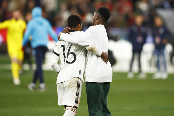 A pitch invader hugs United winger Amad Diallo during the MCG clash with Crystal Palace.