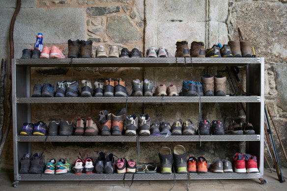 Boots and trainers line a shelf in a hostel on the Santiago road while pilgrims rest.