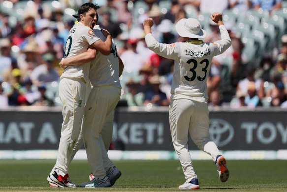 Australia’s Pat Cummins, left, celebrates with teammates after taking the wicket of England’s Joe Root during play on day four.