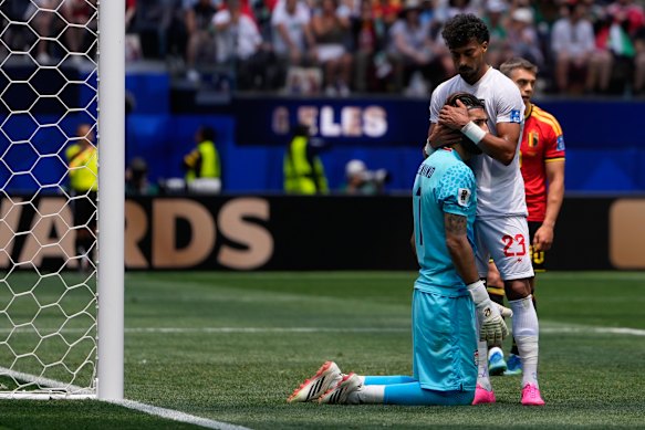 Ramin Rezaeian embraces goalkeeper Alireza Beiranvand.