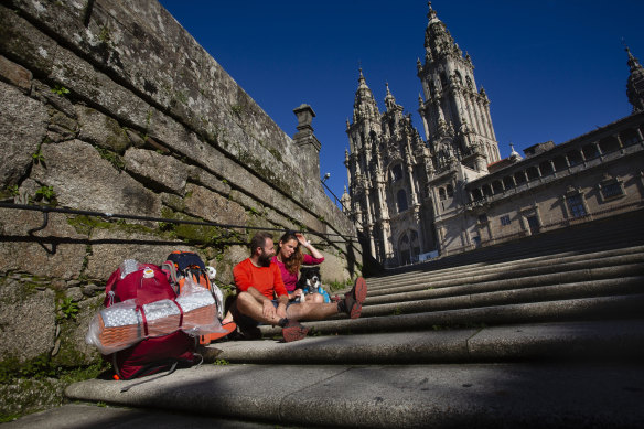 Some pilgrims get immediate benefits – for some it takes years ... two pilgrims rest on the steps of Plaza del Obradoiro.