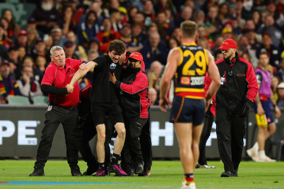 The pitch invader is dragged off by security. 