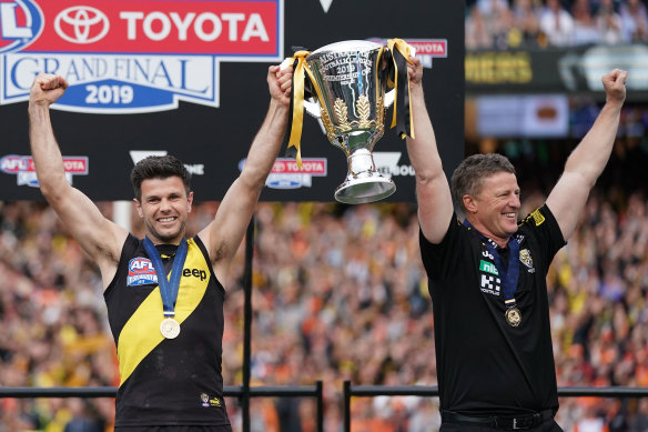 Damien Hardwick, coach of the Tigers and Trent Cotchin of the Tigers hold the premiership trophy aloft .