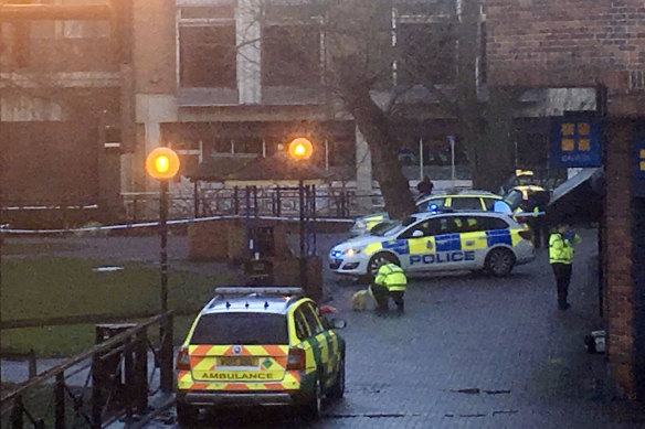 A police officer without protective gear crouches down  next to the bench at the shopping centre where Sergei Skripal and his daughter Yulia were found.