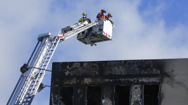 Fire Service staff survey roof damage the day after the fire at Loafers Lodge.