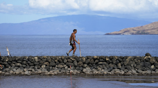 Vicente Ruboi walks along a sea wall in Kihei, Hawaii after the fires destroyed part of Maui.