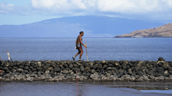 Vicente Ruboi walks along a sea wall in Kihei, Hawaii after the fires destroyed part of Maui.