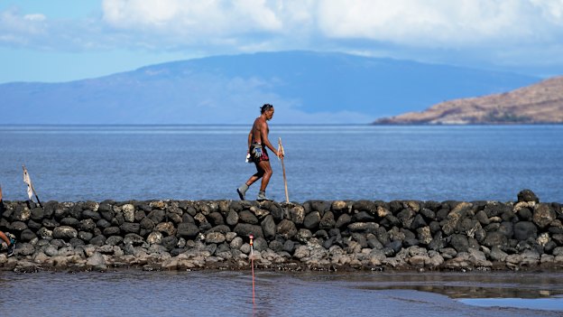 Vicente Ruboi walks along a sea wall in Kihei, Hawaii after the fires destroyed part of Maui.