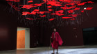 A man wearing traditional Maasai garments walks beneath an installation at the Biennale.