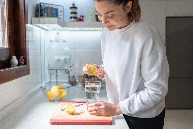 Woman Squeezing A Lemon Into A Glass Of Water