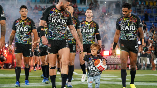 Quaden Bayles, leads the Indigenous All Stars on to the field with captain Joel Thompson.