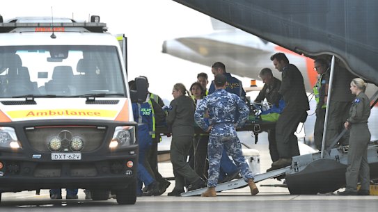 A survivor of the Whaakaari volcanic eruption in New Zealand is removed on a stretcher from a RAAF Hercules at Sydney Airport on Thursday.