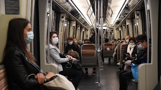 Commuters in protective masks practise social distancing on a train in Paris on Monday.