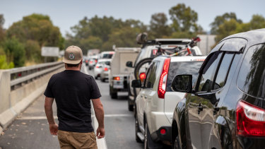 Nathan Goring looks on as a long queue of vehicles forms at the Victorian border near Albury.