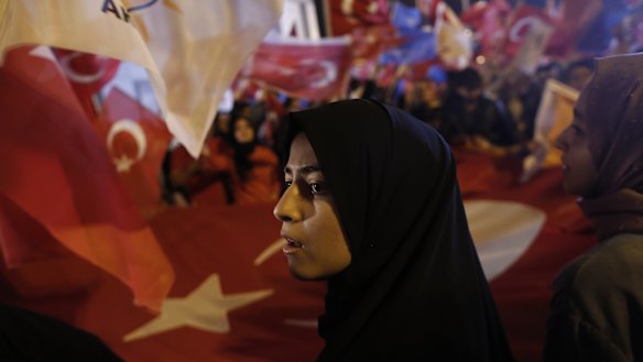 People hold a large Turkish national flag outside of the AKP party headquarters.