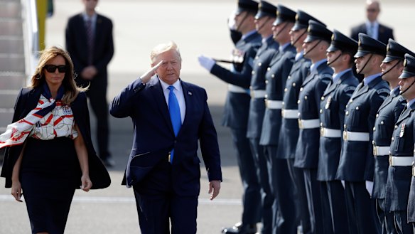 President Donald Trump salutes an honour guard as he and first lady Melania Trump arrive at Stansted Airport in England.