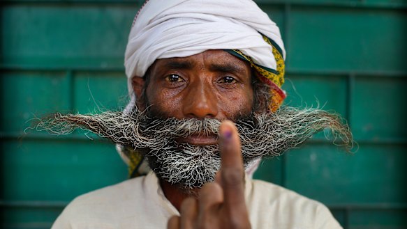 An Indian displays indelible ink mark on his index finger after casting his vote on the outskirts of Varanasi, India.