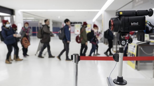 Passengers walk past a thermal scanner upon their arrival at Narita airport in Japan. 