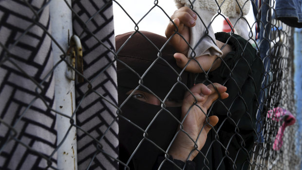 An Islamic State woman at the fence line of the foreign section of al-Hawl camp in Syria.