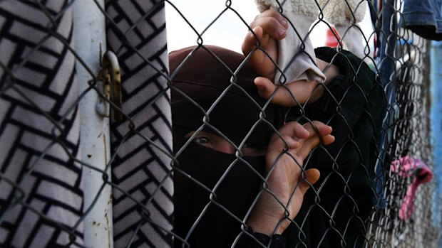 An Islamic State woman at the fence line of the foreign section of al-Hawl camp in Syria.