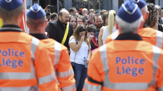 Women cry as they stand next to police officers for a moment of silence on Wednesday for shooting victims near the City Hall in Liege, Belgium.